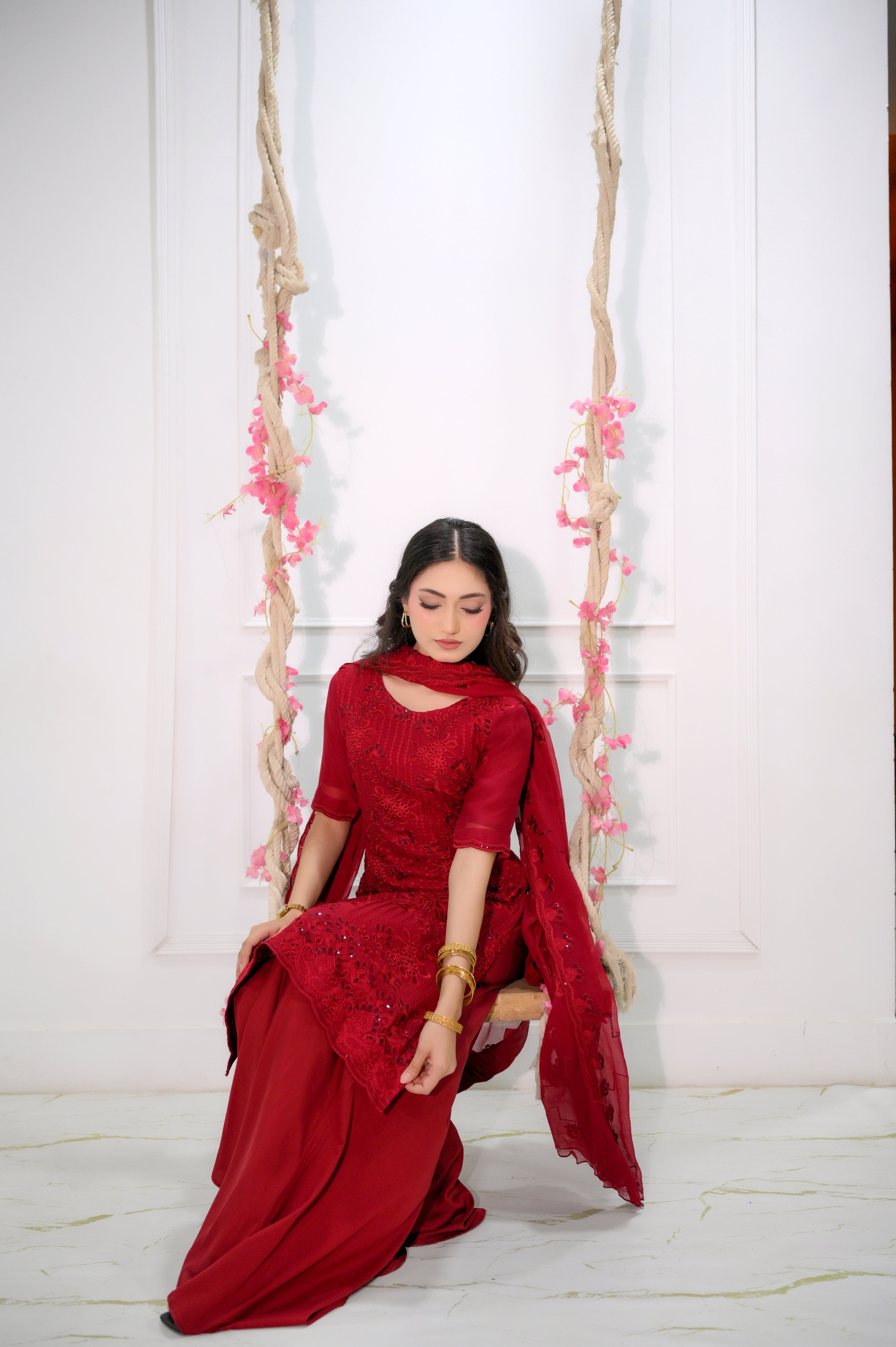 Ruby Bloom red embroidered sharara suit seated festive pose — Faith3 Womens Pakistan